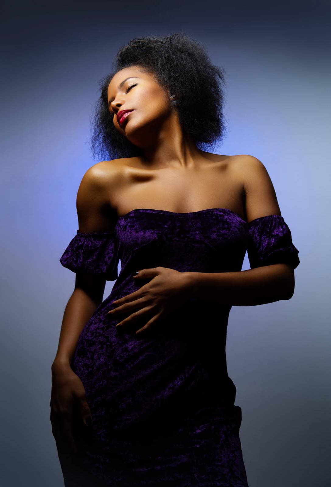 Portrait en studio d'une femme en robe violette, lumière latérale sur fond sombre