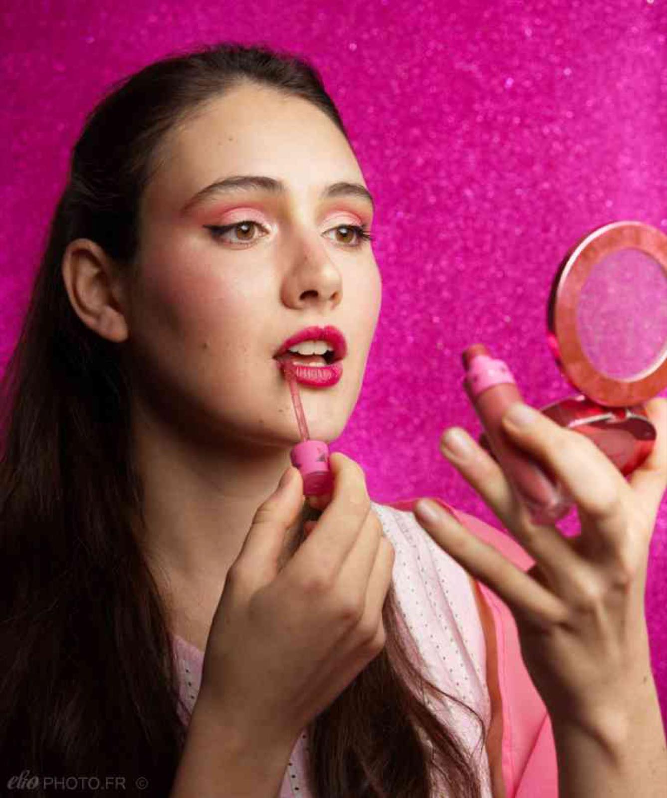 Portrait maquillage sur fond rose, miroir à la main